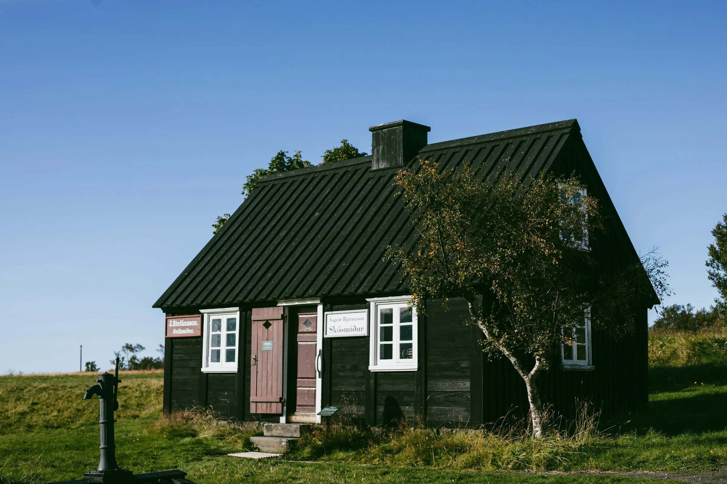 Svartmalt trehus med hvite vinduer på en gressmark